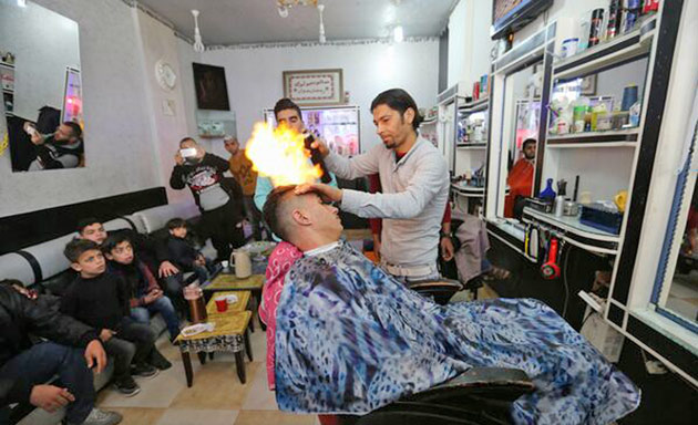 Un frizer din Gaza oferă clienților săi servicii de îndreptare a părului cu... flacăra 