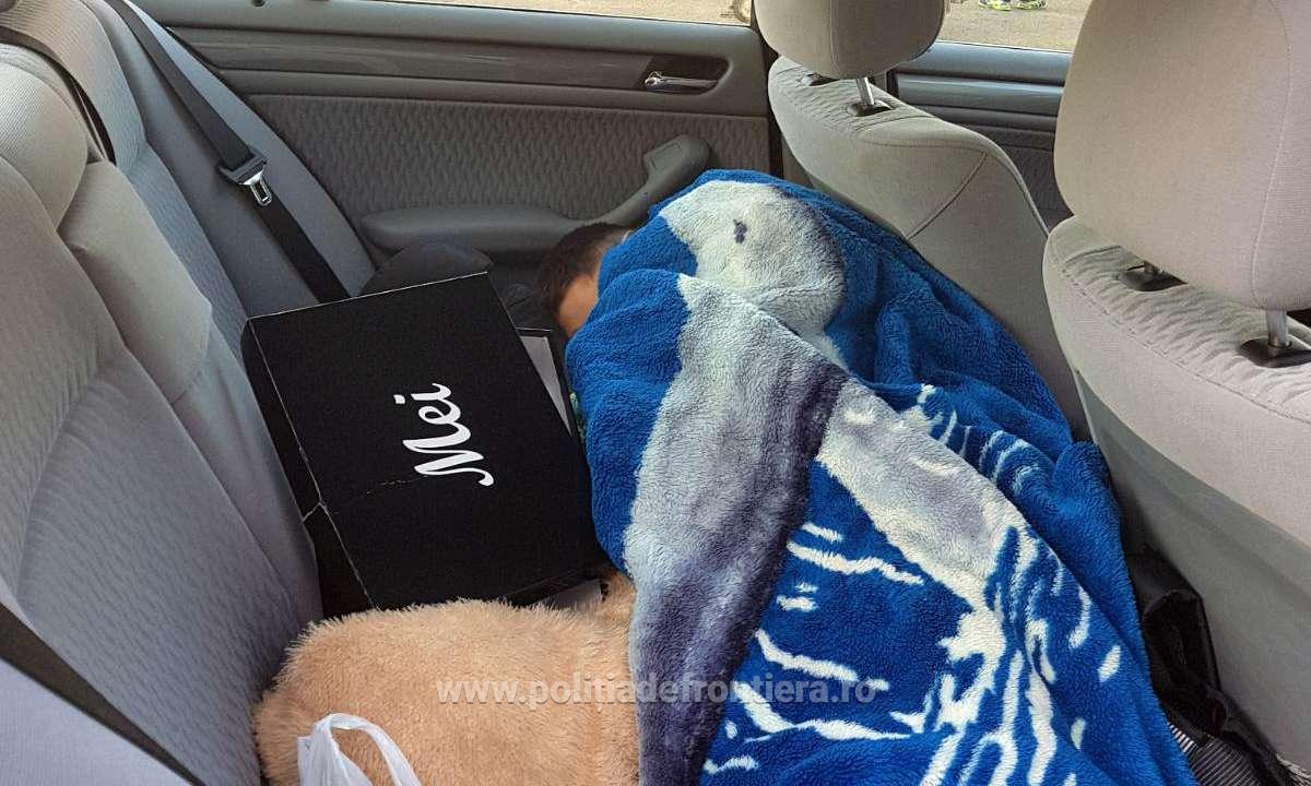 Minor ascuns sub o pătură, pe bancheta din spate a unui autoturism